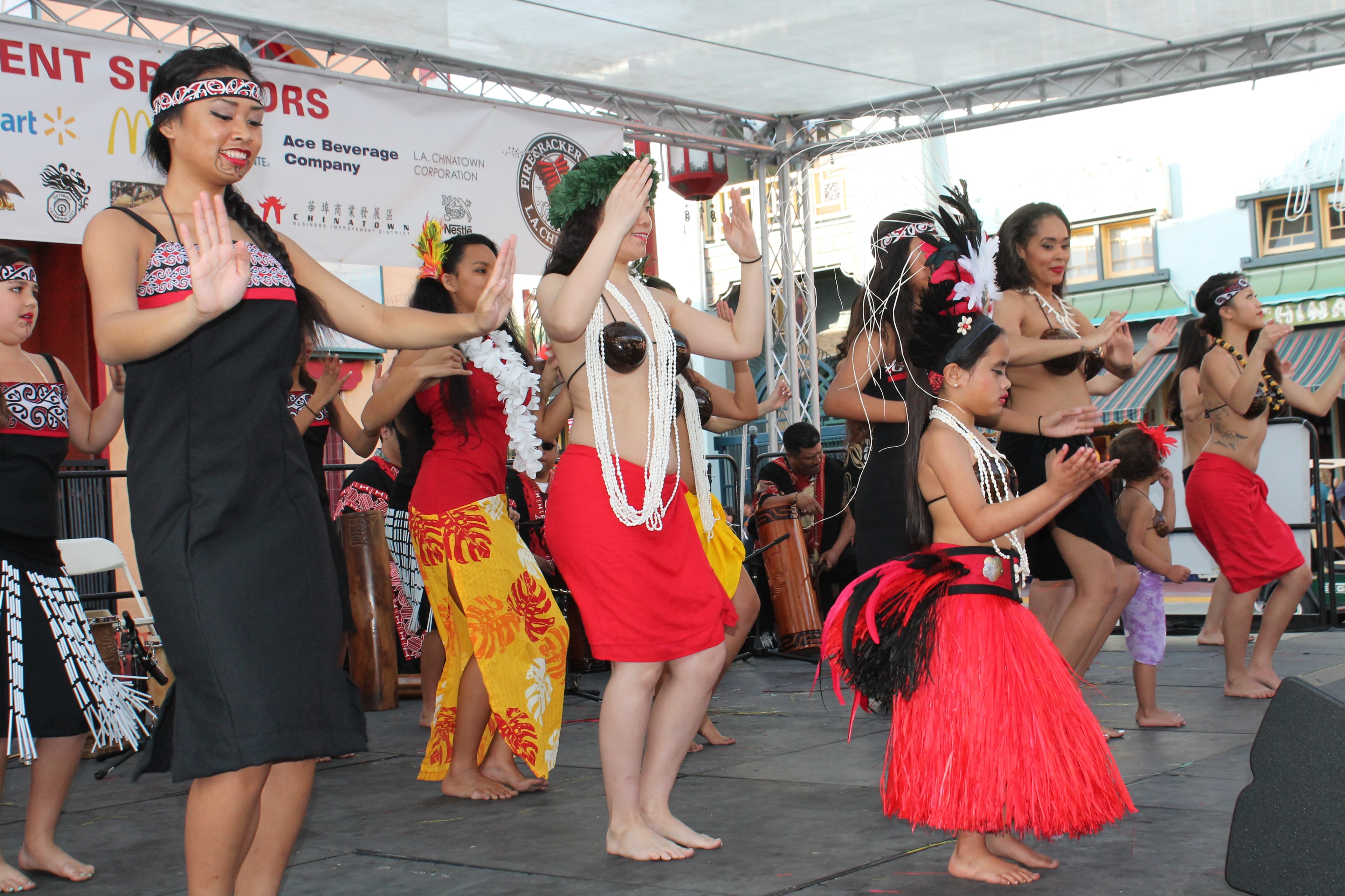 Large group of Polynesian dancers performing on an outdoor stage